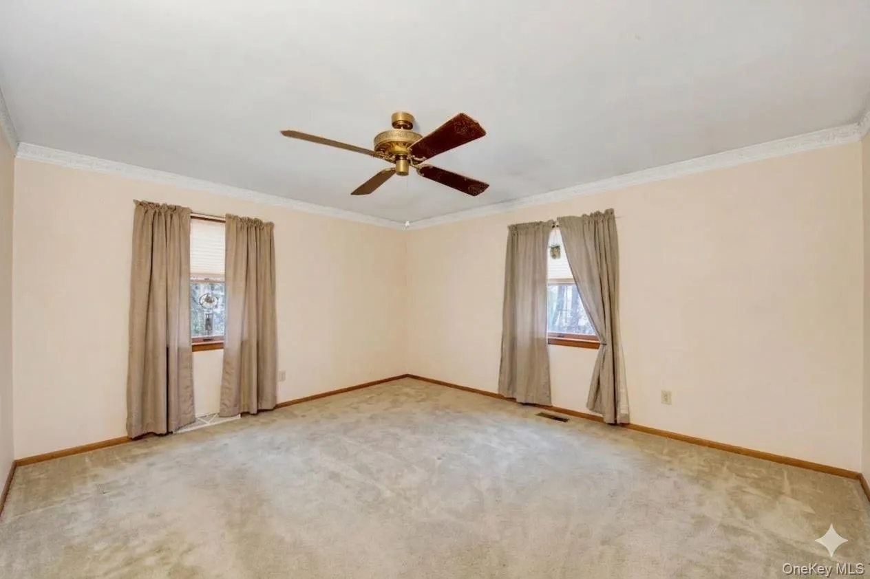 Empty room featuring a ceiling fan, ornamental molding, and light carpet Empty room featuring a ceiling fan, ornamental molding, and light carpet