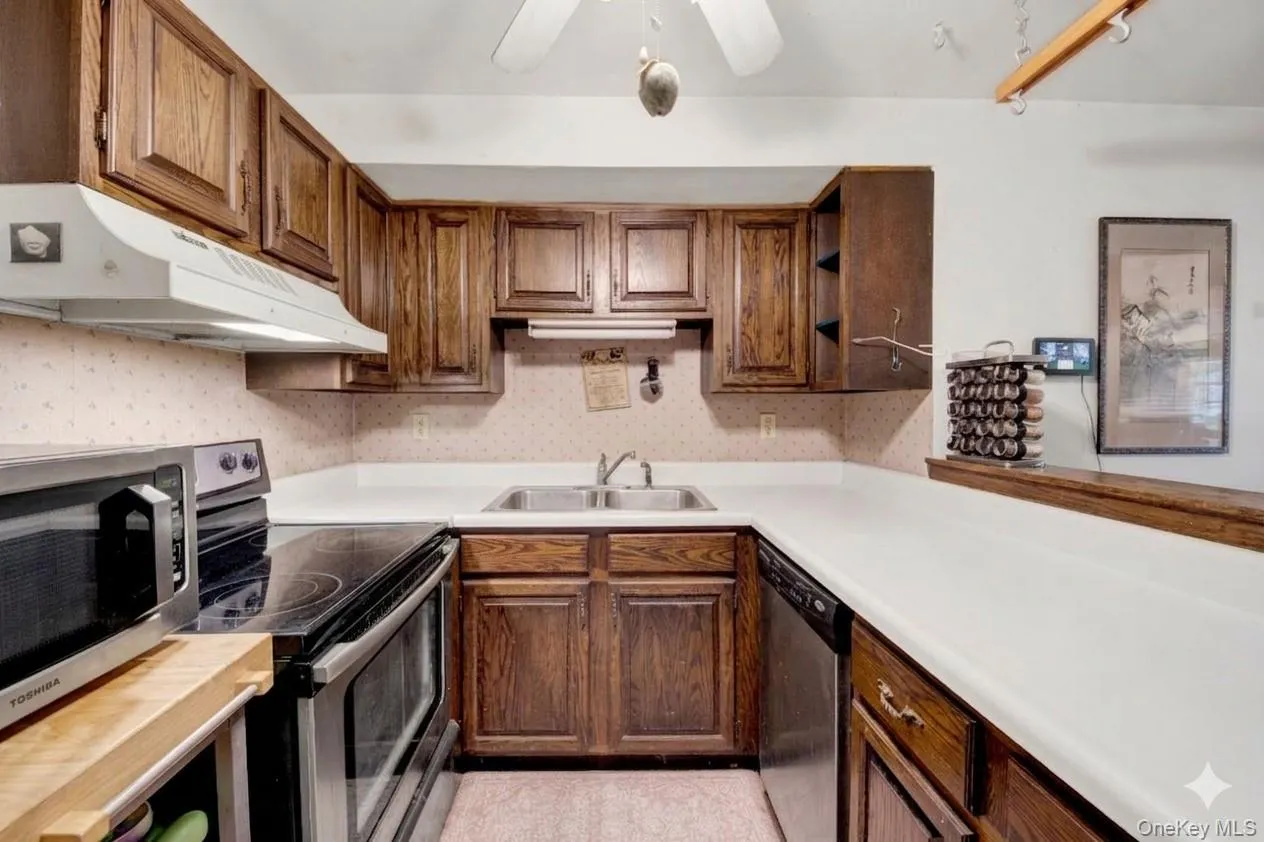 Kitchen featuring stainless steel appliances, open shelves, a ceiling fan, and light countertops Kitchen featuring stainless steel appliances, open shelves, a ceiling fan, and light countertops