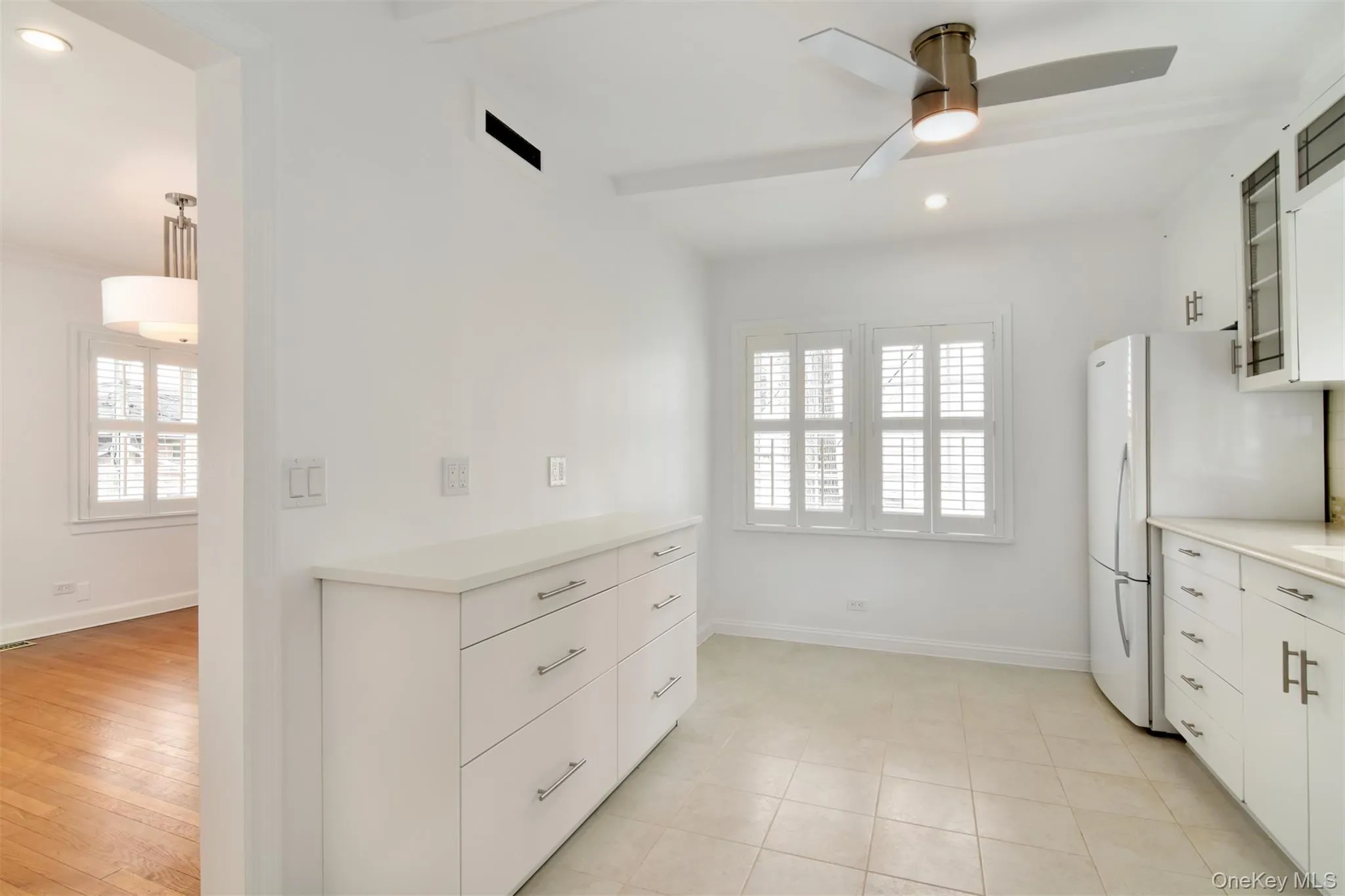 Kitchen with white cabinetry, glass fronted cabinets, recessed lighting, freestanding refrigerator, and plenty of natural light Kitchen with white cabinetry, glass fronted cabinets, recessed lighting, freestanding refrigerator, and plenty of natural light