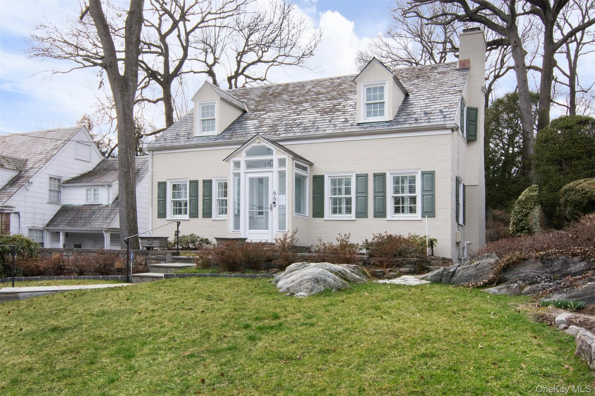 New England style home with a slate roof, a front yard, and a chimney New England style home with a slate roof, a front yard, and a chimney