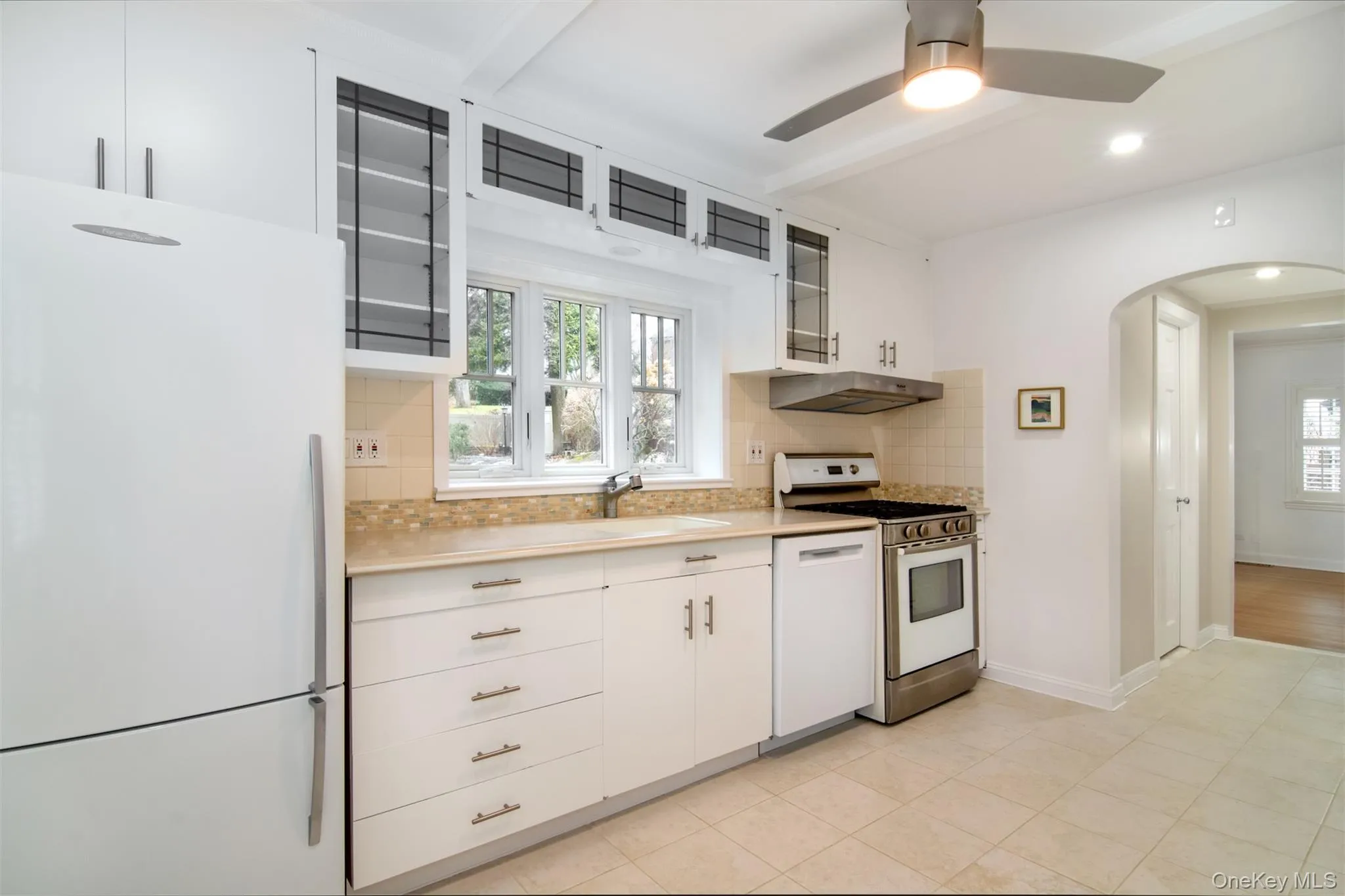 Recently renovated Kitchen with white cabinets, white appliances, arched walkways, light countertops, and recessed lighting Recently renovated Kitchen with white cabinets, white appliances, arched walkways, light countertops, and recessed lighting