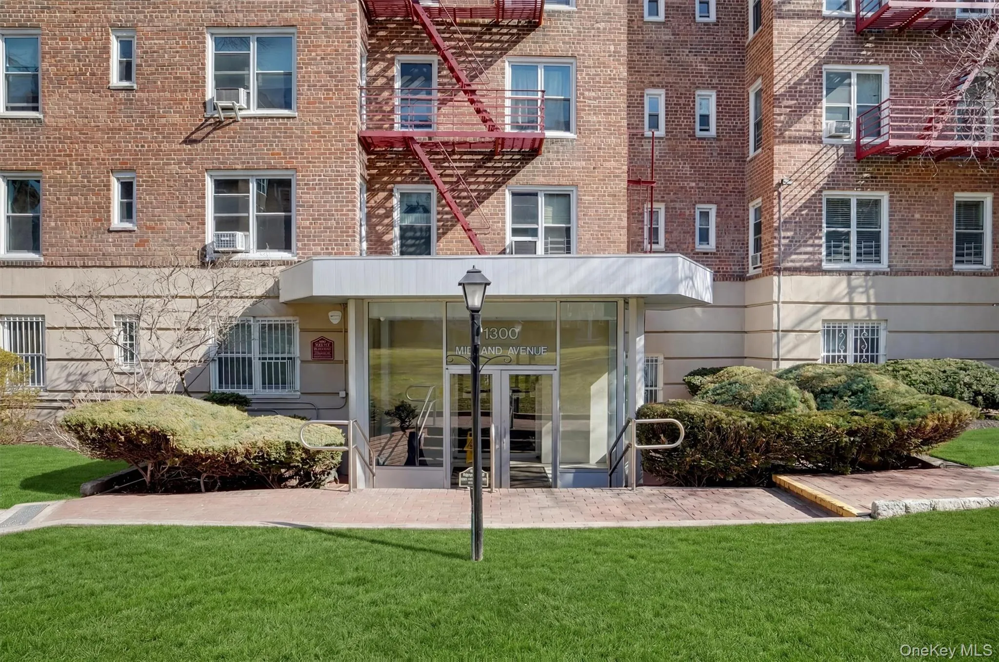 Brick building exterior with a prominent glass entry, white canopy, and metal handrails Brick building exterior with a prominent glass entry, white canopy, and metal handrails