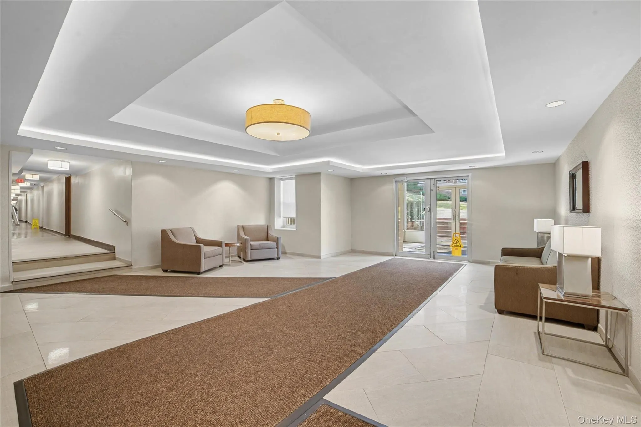 Spacious common area featuring recessed lighting, a central drum pendant light, and light-toned tile flooring Spacious common area featuring recessed lighting, a central drum pendant light, and light-toned tile flooring