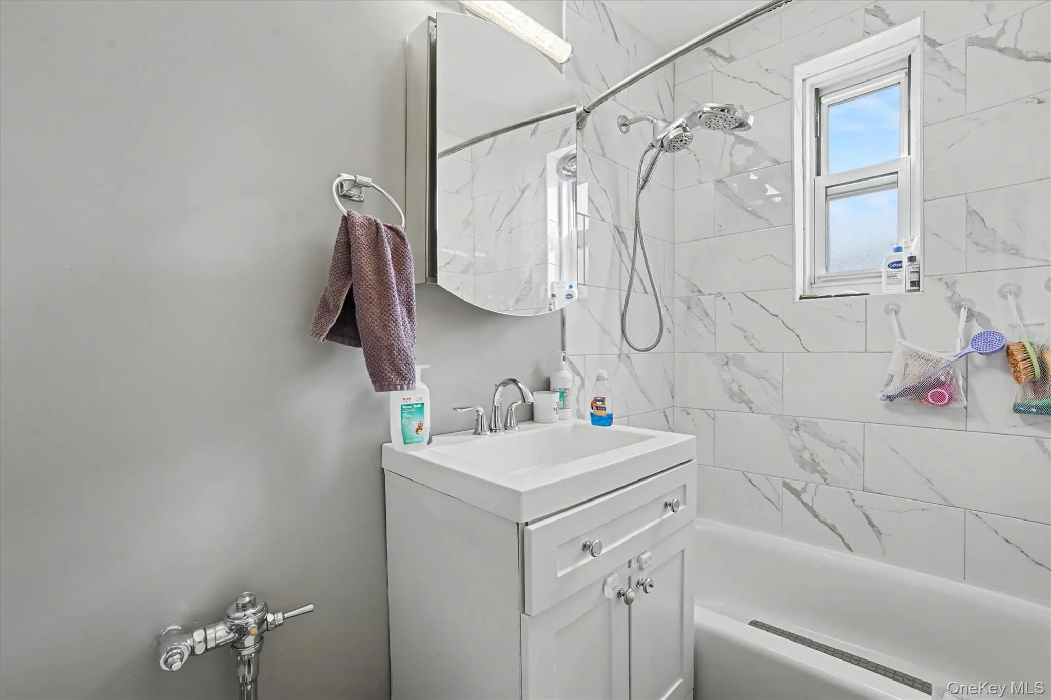 Bathroom featuring a white vanity with integrated sink, chrome faucet, and mirrored medicine cabinet Bathroom featuring a white vanity with integrated sink, chrome faucet, and mirrored medicine cabinet