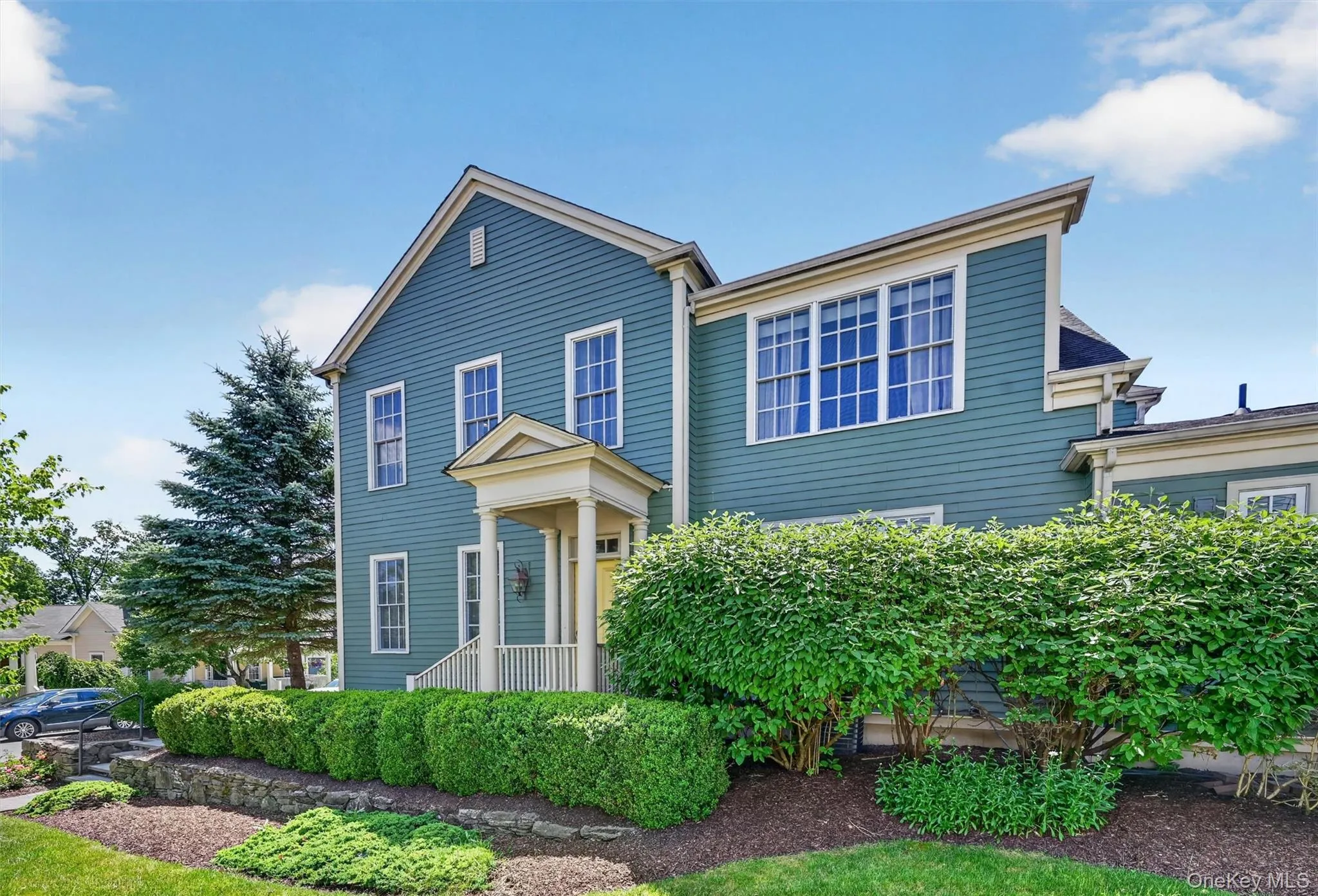 The front exterior of the home (which is perpendicular to the street) offers a timeless look with green siding, crisp trim, lush landscaping, and a welcoming covered entry The front exterior of the home (which is perpendicular to the street) offers a timeless look with green siding, crisp trim, lush landscaping, and a welcoming covered entry