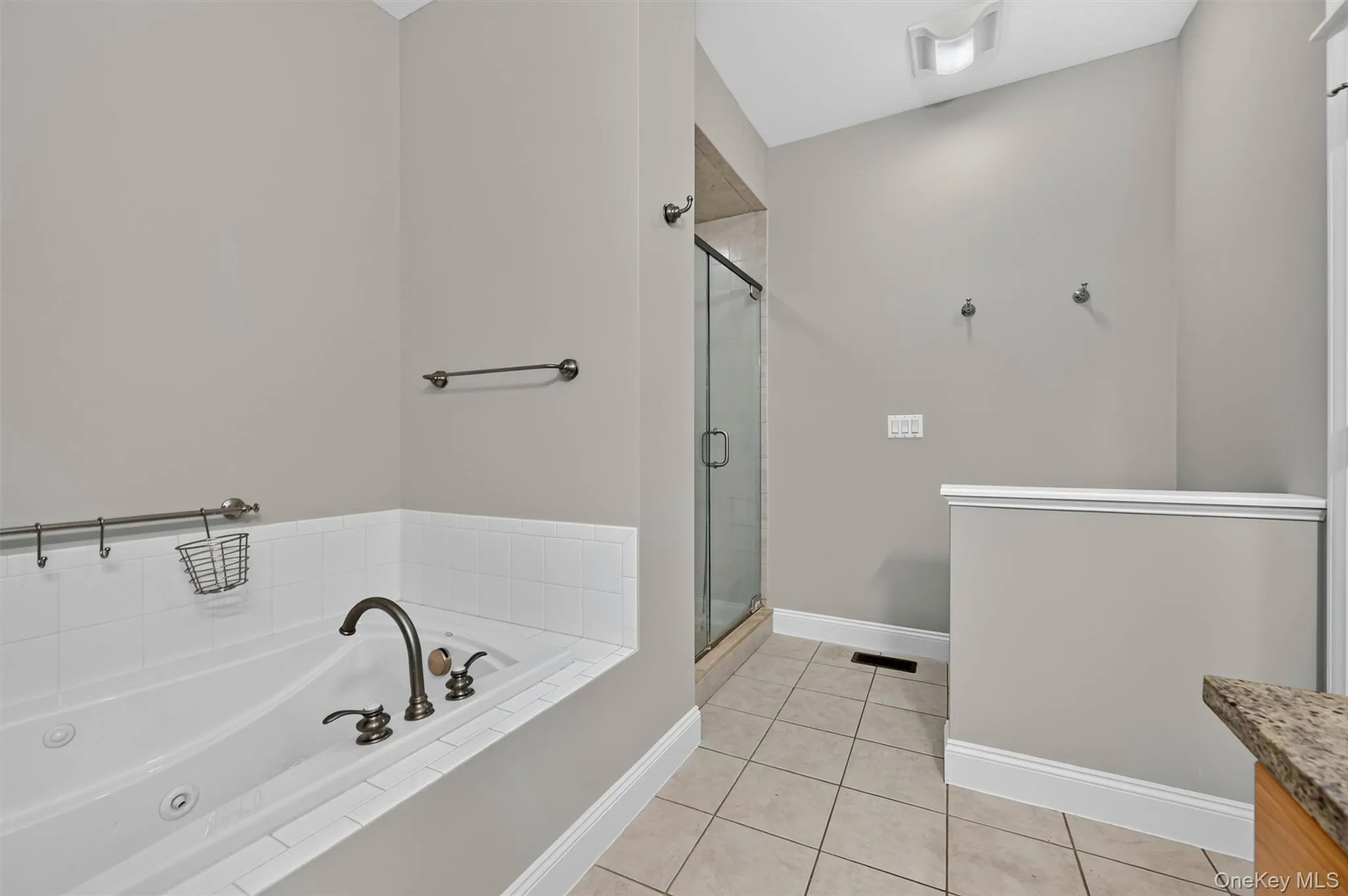 This angle of the primary bathroom shows the shower beyond the soaking tub, with a half wall providing added privacy for the toilet area. This angle of the primary bathroom shows the shower beyond the soaking tub, with a half wall providing added privacy for the toilet area.