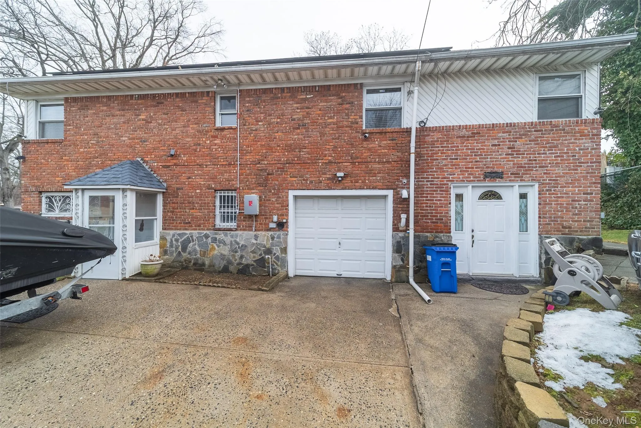 Rear view of property with a garage, driveway, and brick siding Rear view of property with a garage, driveway, and brick siding
