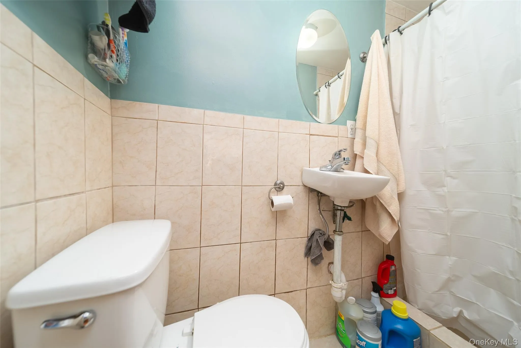 Bathroom featuring a shower with shower curtain and tile walls Bathroom featuring a shower with shower curtain and tile walls