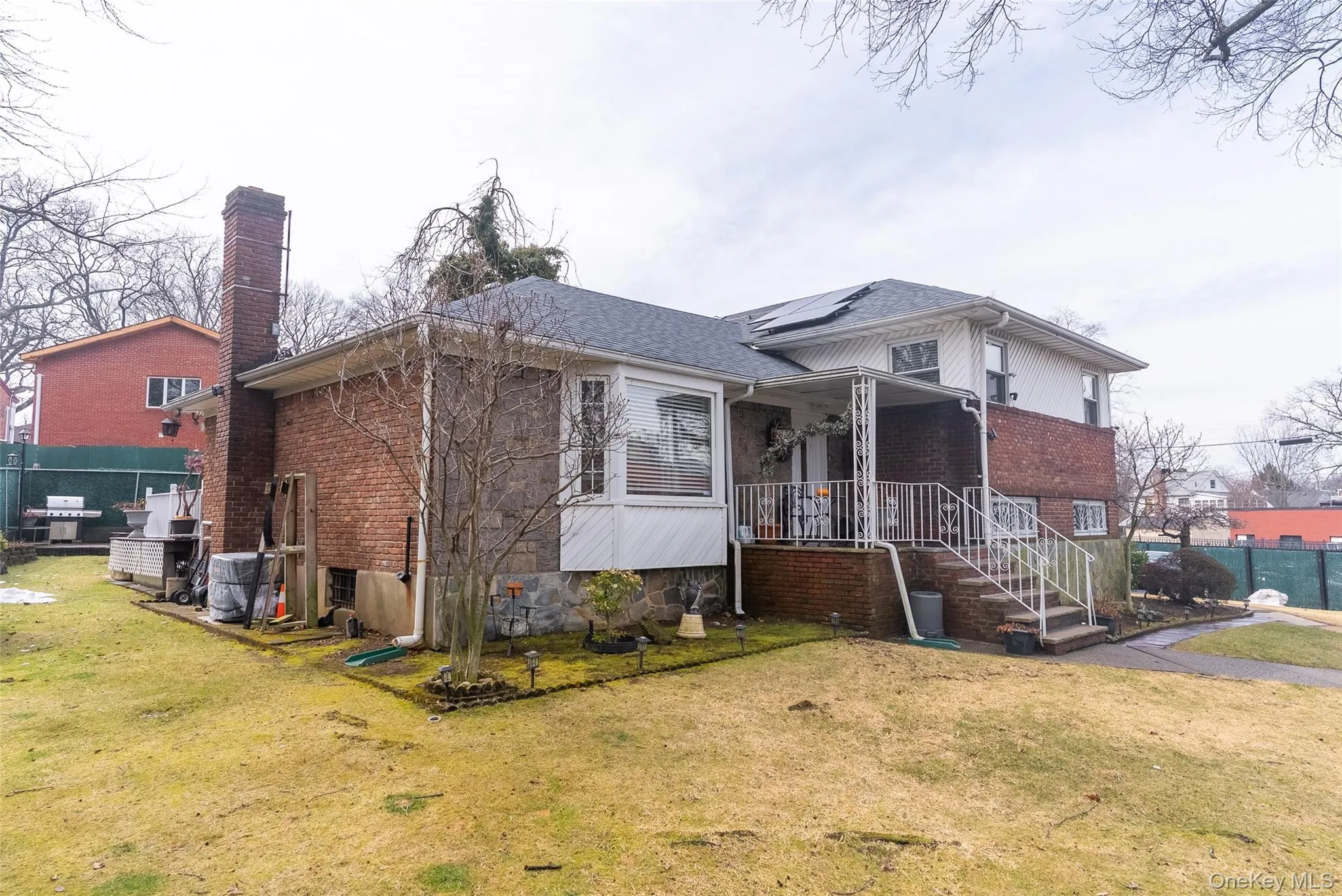 View of front of house with roof mounted solar panels, brick siding, a chimney, and covered porch View of front of house with roof mounted solar panels, brick siding, a chimney, and covered porch