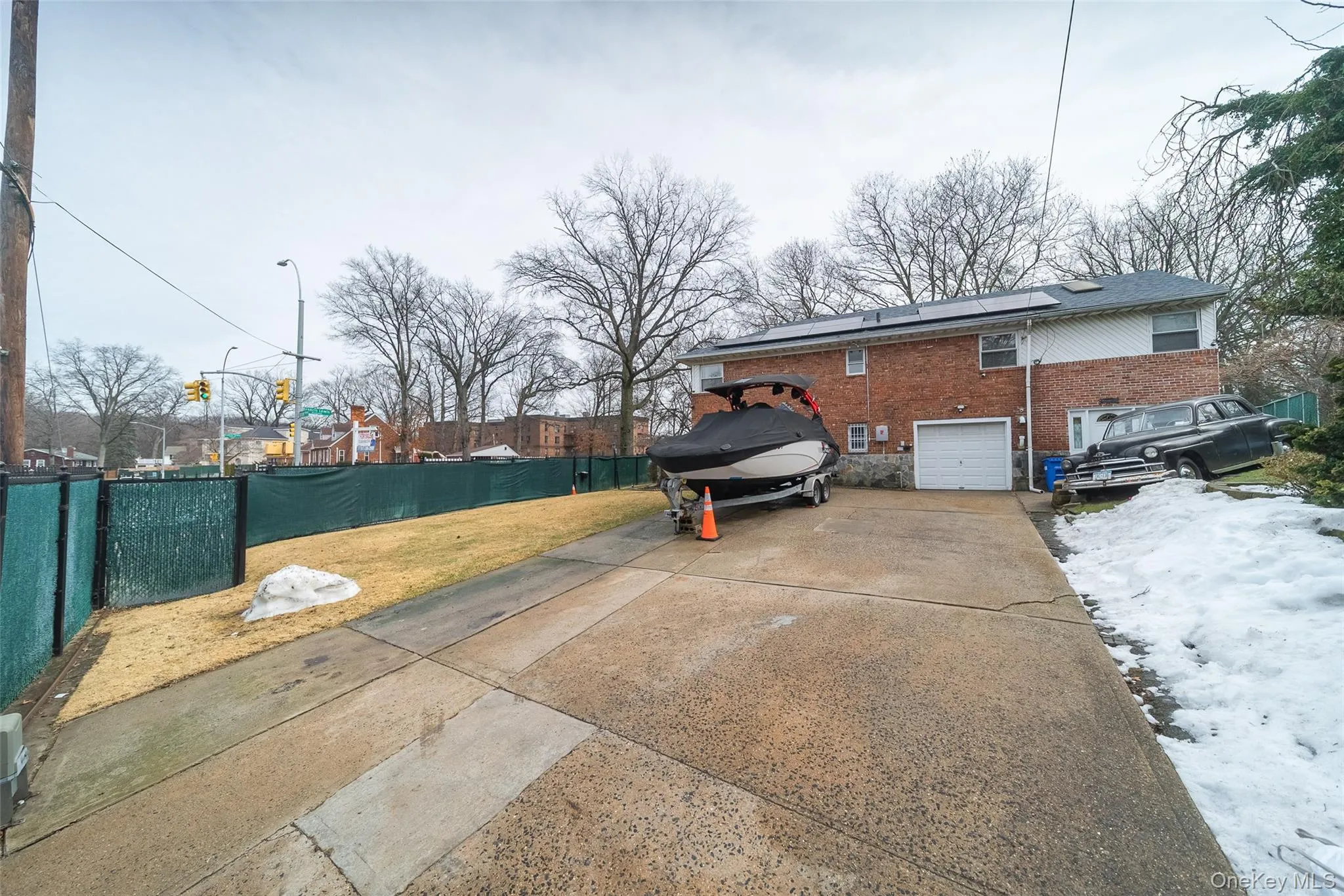 View of side of property featuring concrete driveway, brick siding, an attached garage, and roof mounted solar panels View of side of property featuring concrete driveway, brick siding, an attached garage, and roof mounted solar panels