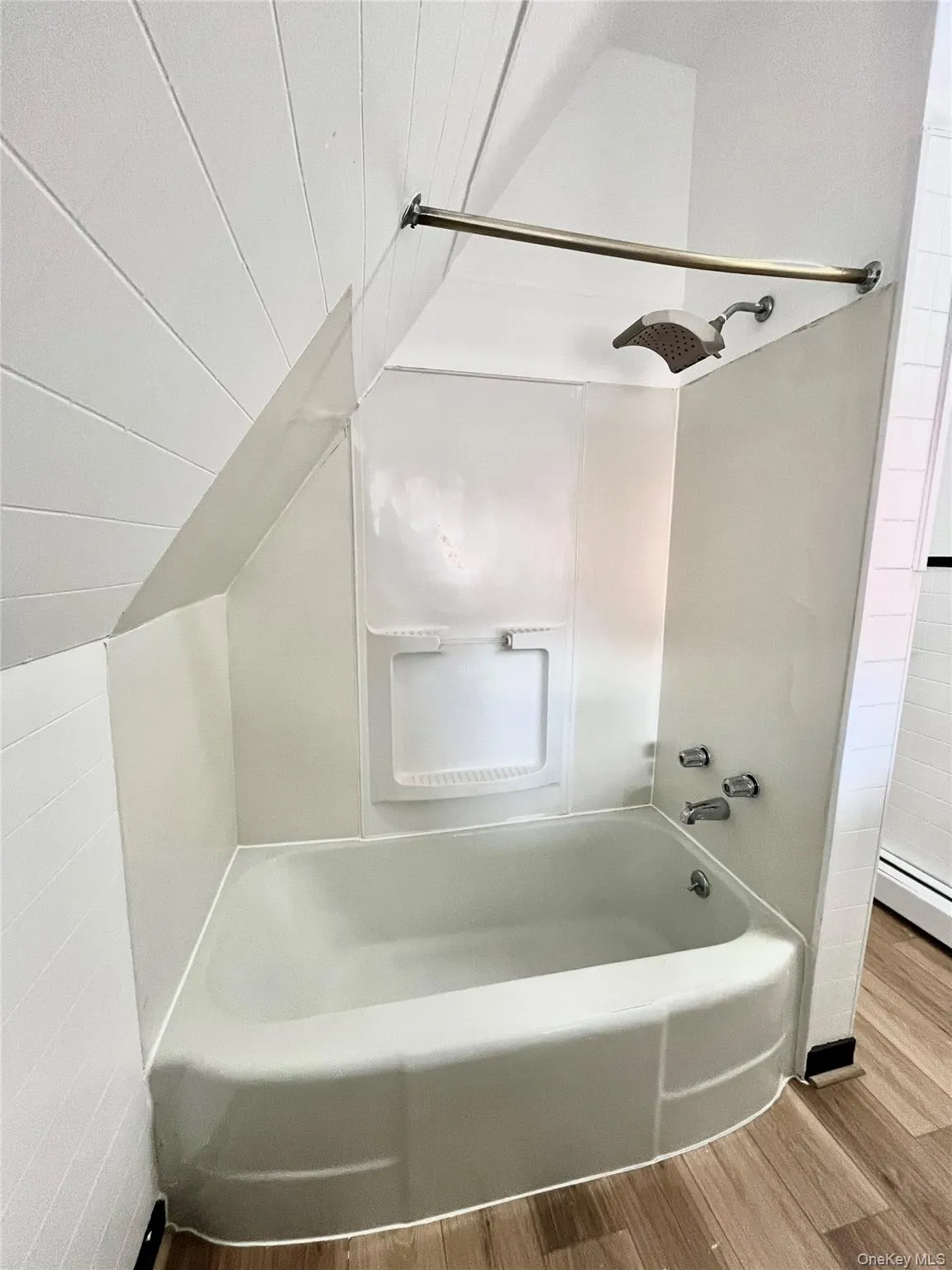 Bathroom featuring vaulted ceiling, wood finished floors, a baseboard heating unit, and washtub / shower combination Bathroom featuring vaulted ceiling, wood finished floors, a baseboard heating unit, and washtub / shower combination