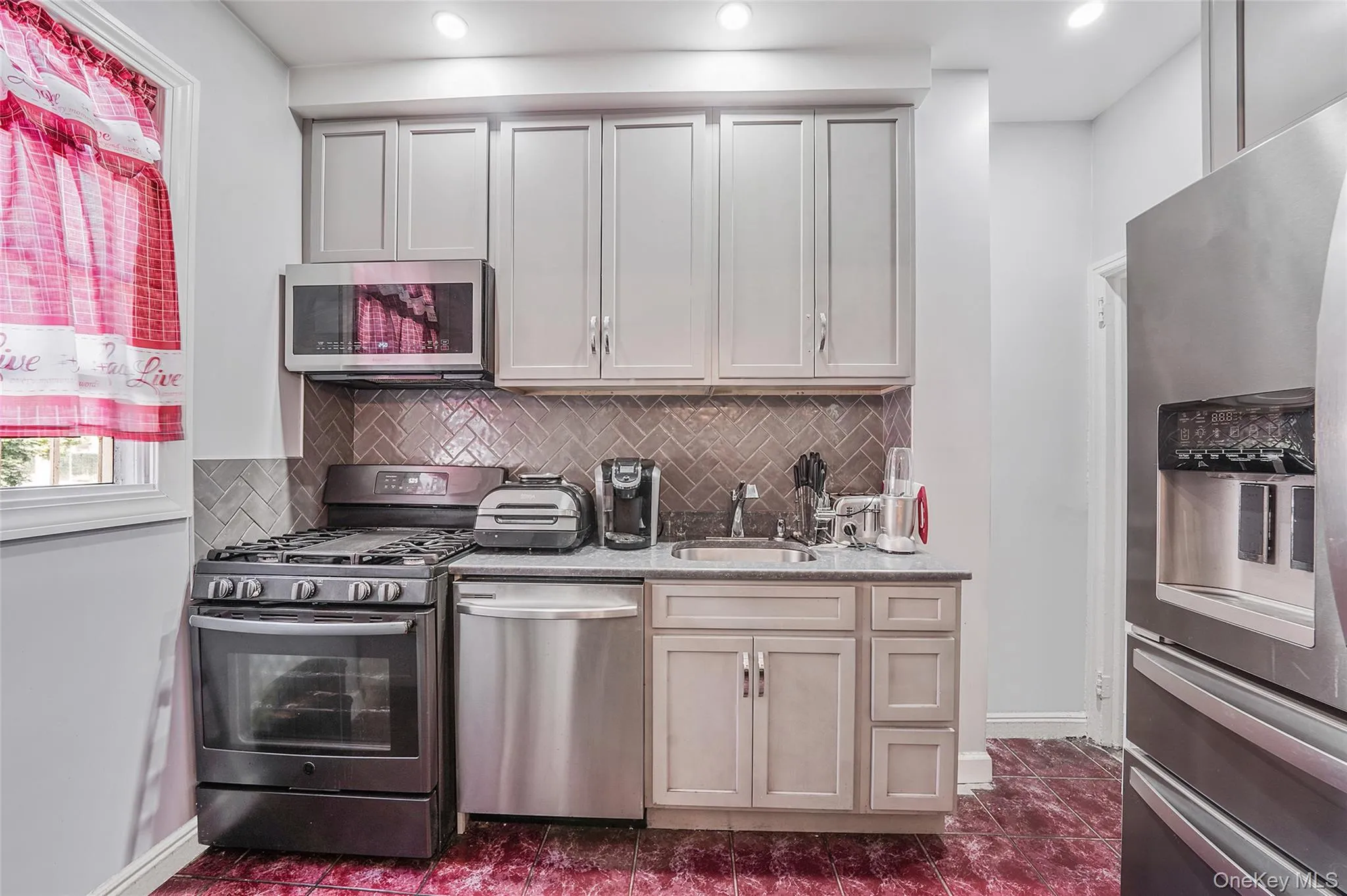 Kitchen featuring appliances with stainless steel finishes, decorative backsplash, recessed lighting, and light stone counters Kitchen featuring appliances with stainless steel finishes, decorative backsplash, recessed lighting, and light stone counters