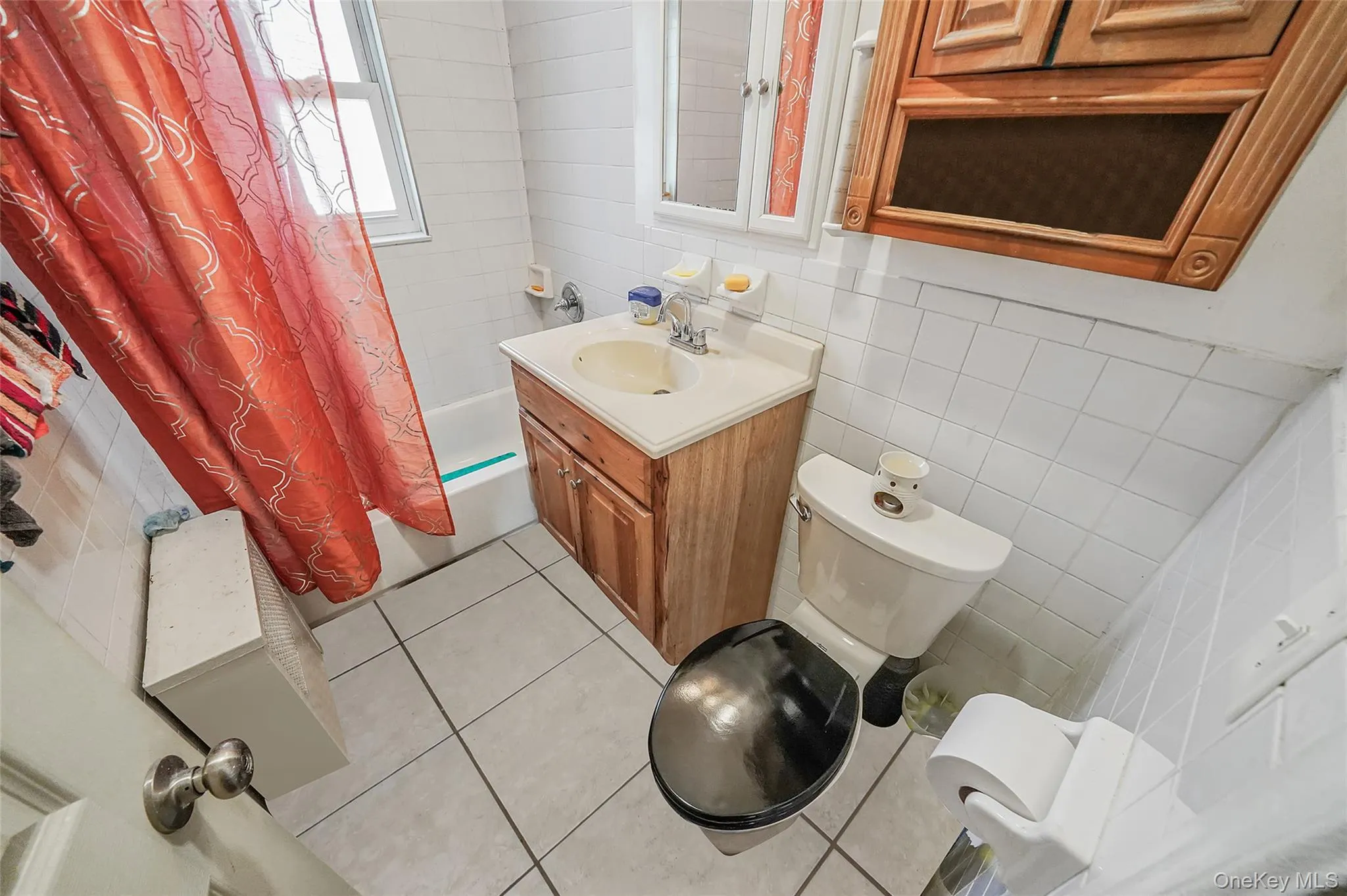 Full bath with tile walls, shower / bath combination with curtain, vanity, tile patterned floors, and backsplash Full bath with tile walls, shower / bath combination with curtain, vanity, tile patterned floors, and backsplash