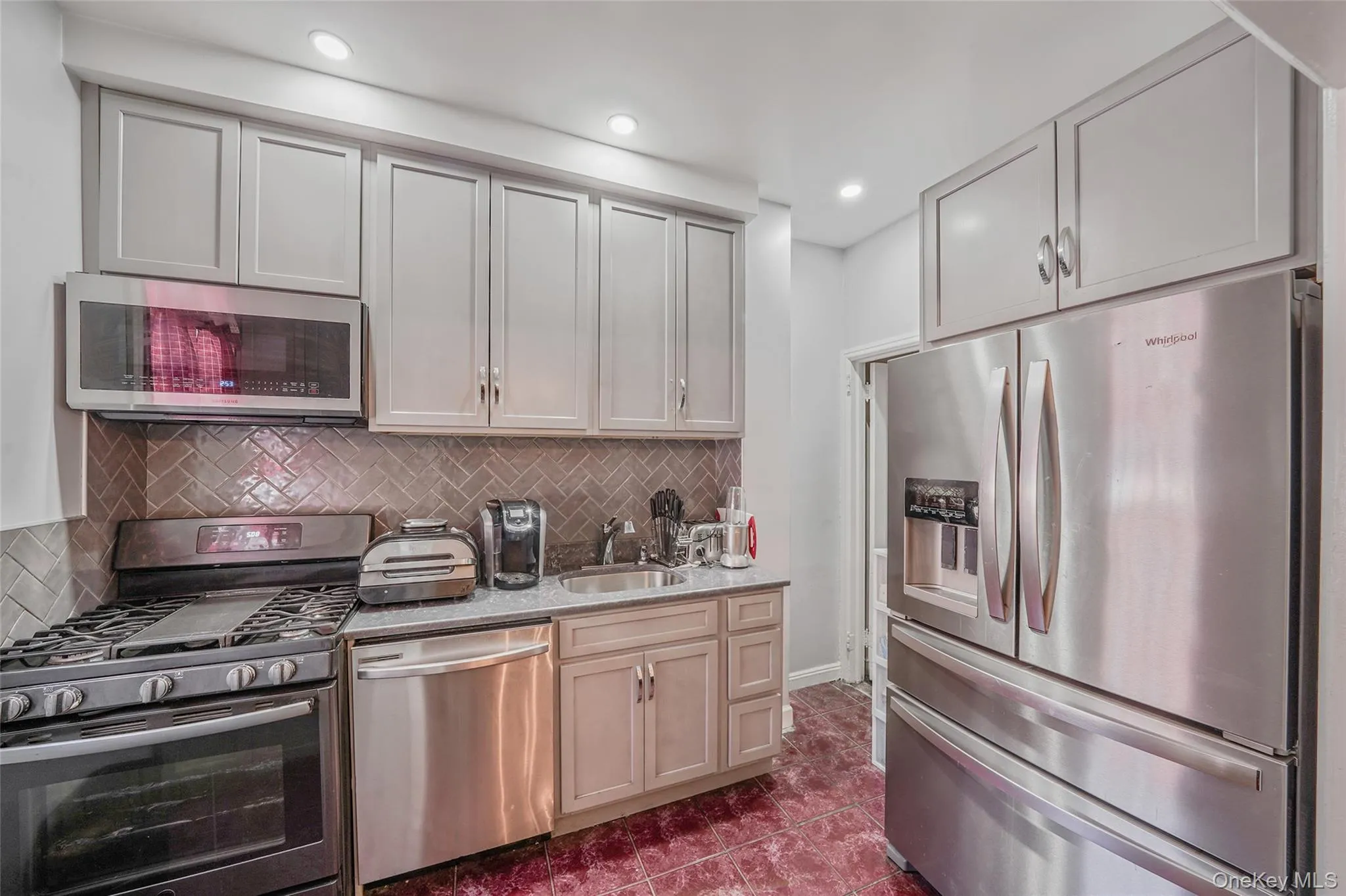 Kitchen featuring stainless steel appliances, decorative backsplash, dark tile patterned flooring, and recessed lighting Kitchen featuring stainless steel appliances, decorative backsplash, dark tile patterned flooring, and recessed lighting