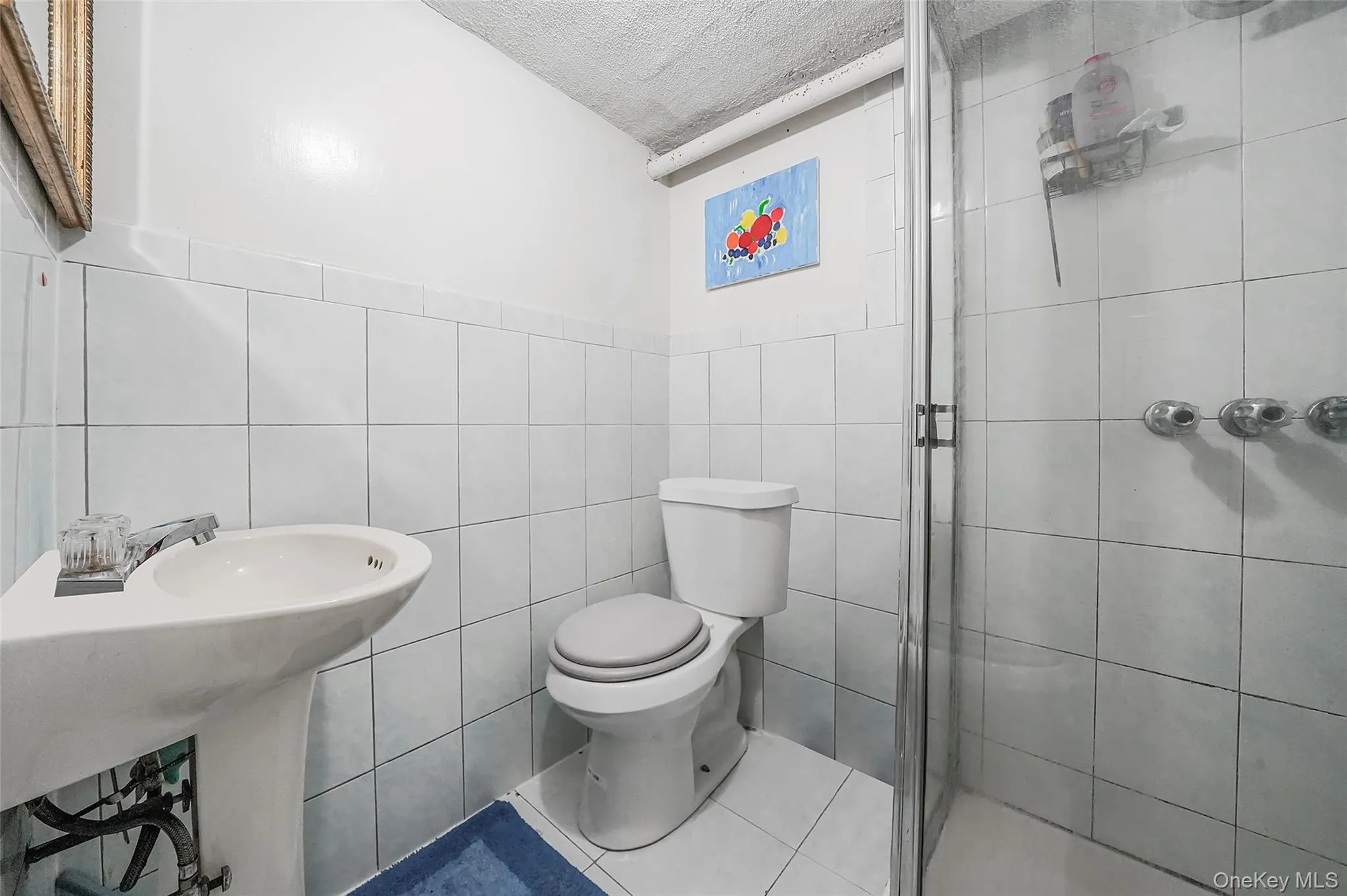 Bathroom featuring tile walls, a shower stall, a textured ceiling, and tile patterned flooring Bathroom featuring tile walls, a shower stall, a textured ceiling, and tile patterned flooring