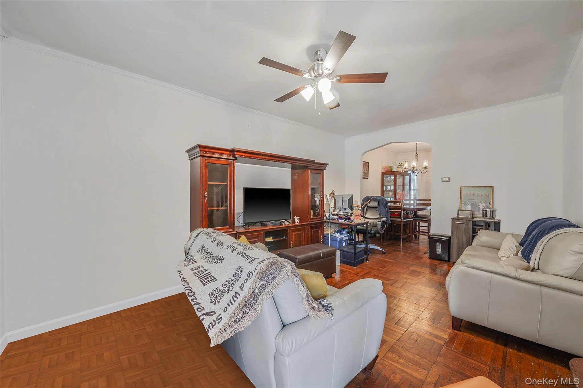 Living room with a chandelier, a ceiling fan, crown molding, and arched walkways Living room with a chandelier, a ceiling fan, crown molding, and arched walkways