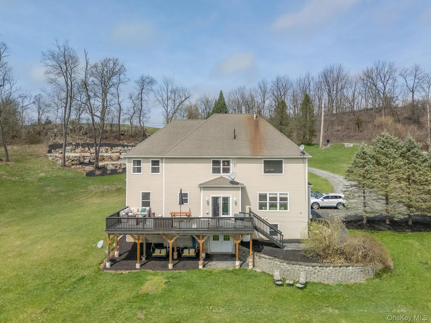 Rear elevation showcasing the expansive deck and walk-out lower level, overlooking the open property and surrounding landscape. Rear elevation showcasing the expansive deck and walk-out lower level, overlooking the open property and surrounding landscape.
