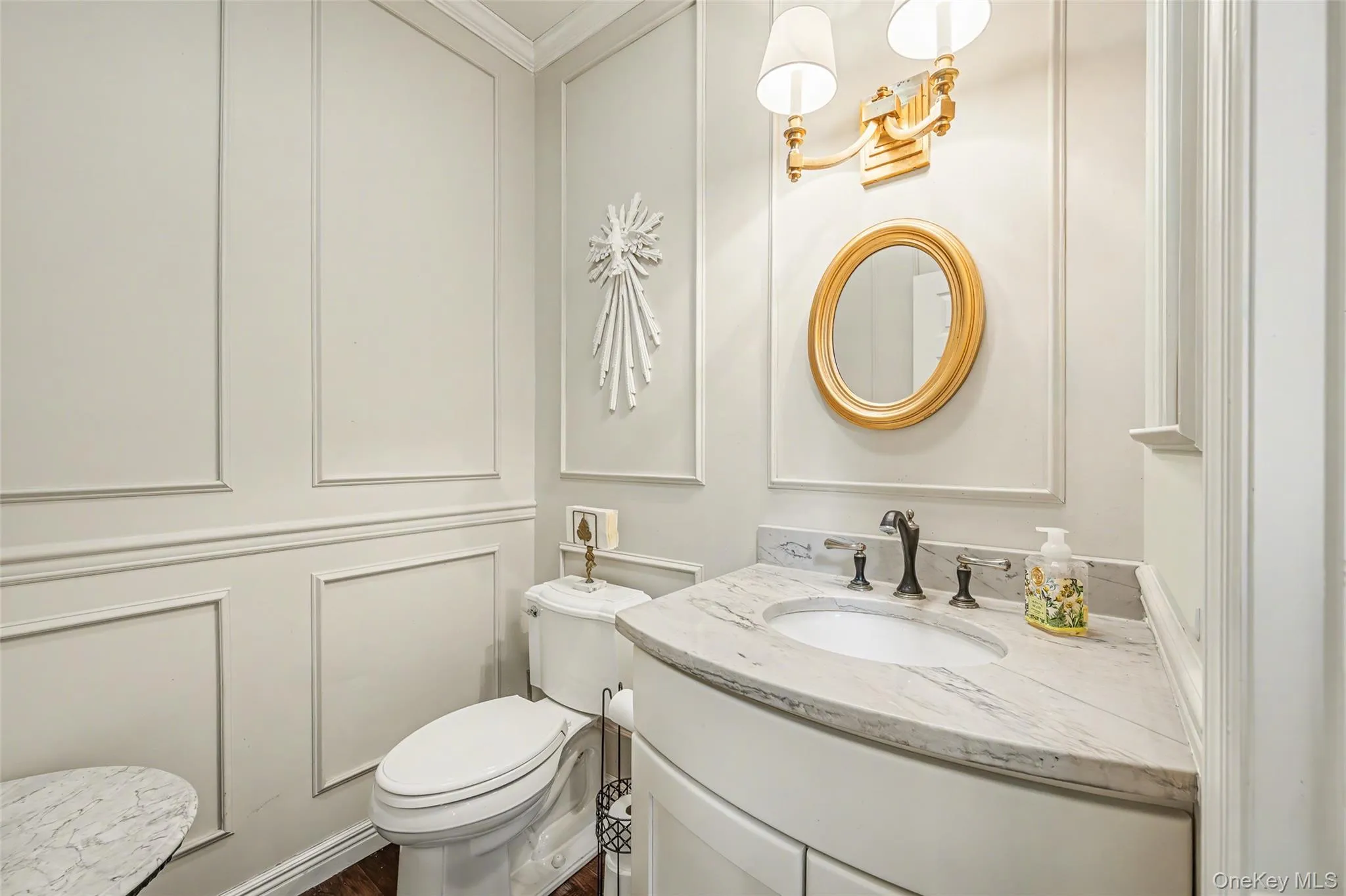 Stylish powder room featuring elegant millwork, a marble-top vanity, and refined finishes. Stylish powder room featuring elegant millwork, a marble-top vanity, and refined finishes.