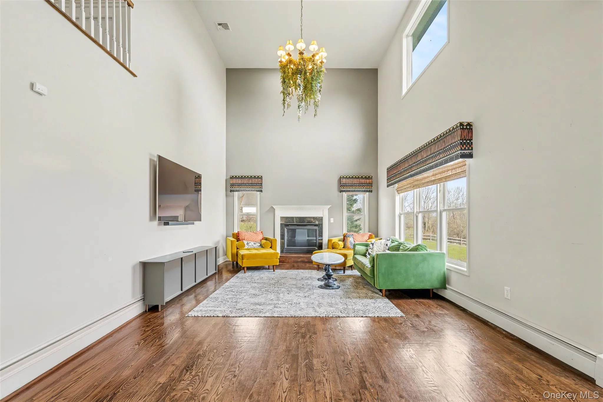 Dramatic double-height living space anchored by a fireplace, creating a warm and inviting setting with abundant natural light. A few personal items have been edited from this image. Dramatic double-height living space anchored by a fireplace, creating a warm and inviting setting with abundant natural light. A few personal items have been edited from this image.