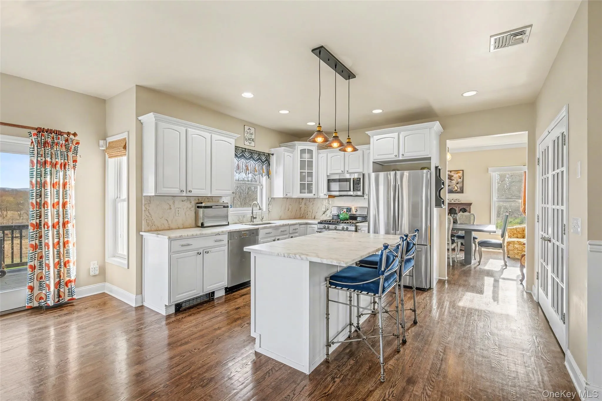 Bright and spacious kitchen featuring a center island with seating, ample cabinetry, and a seamless connection to the dining area and outdoor deck. Bright and spacious kitchen featuring a center island with seating, ample cabinetry, and a seamless connection to the dining area and outdoor deck.