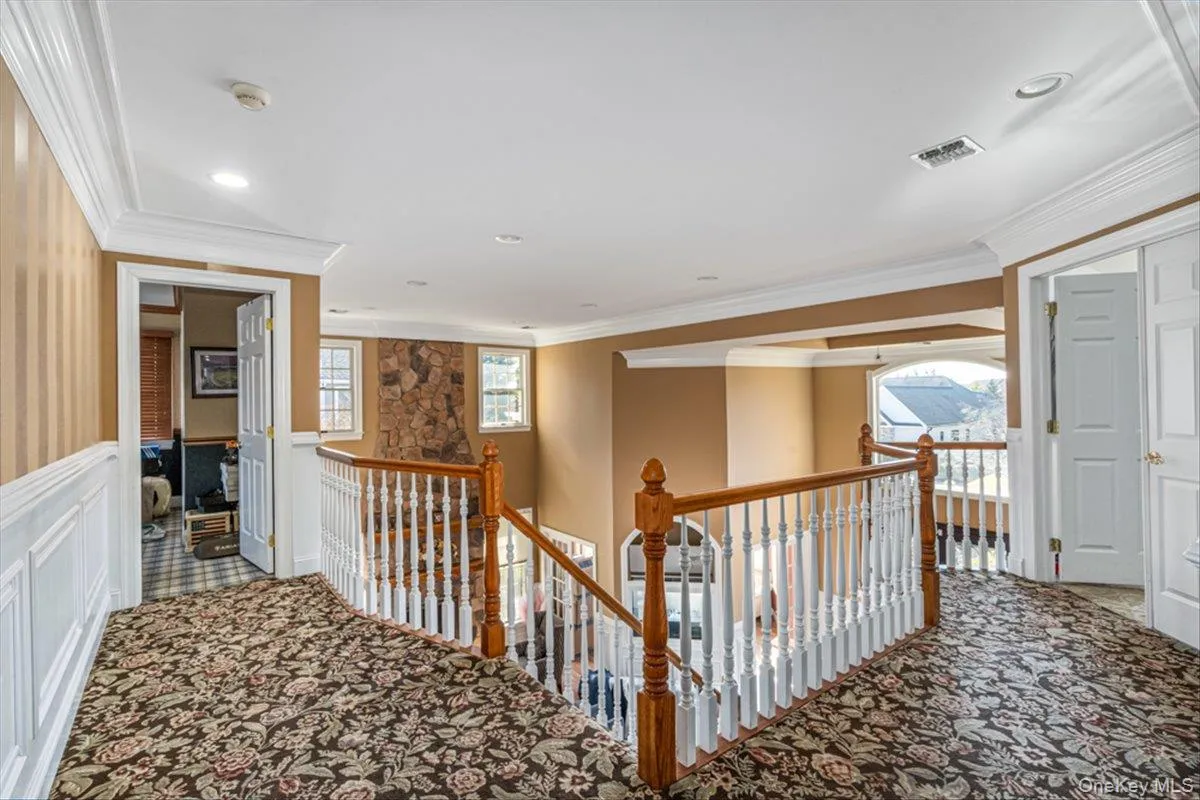 Corridor with an upstairs landing, carpet floors, and crown molding Corridor with an upstairs landing, carpet floors, and crown molding