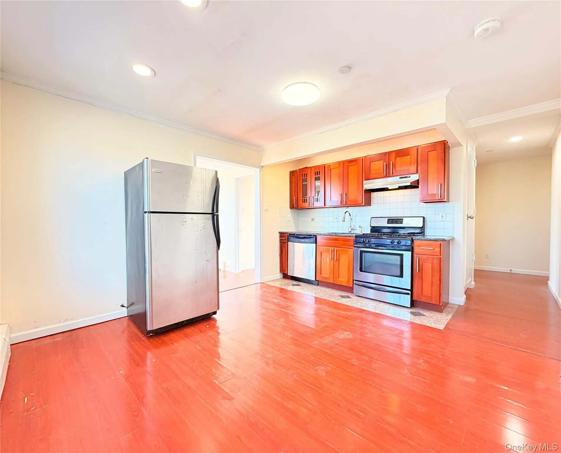 Kitchen with stainless steel appliances, wood finish cabinetry, glass fronted cabinets, crown molding, and light wood-type flooring Kitchen with stainless steel appliances, wood finish cabinetry, glass fronted cabinets, crown molding, and light wood-type flooring