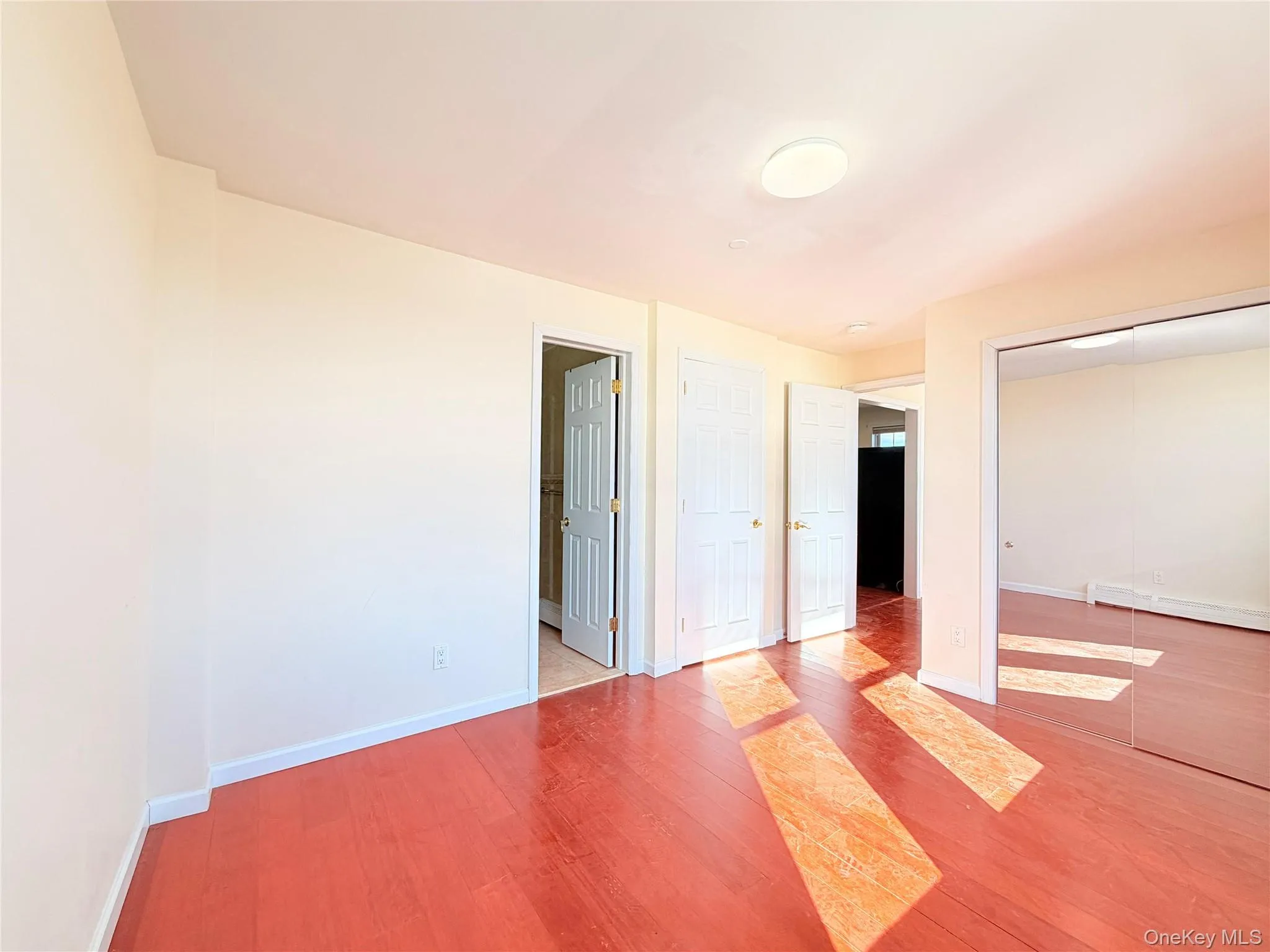 Unfurnished bedroom featuring light wood-style floors, a closet, and a baseboard heating unit Unfurnished bedroom featuring light wood-style floors, a closet, and a baseboard heating unit