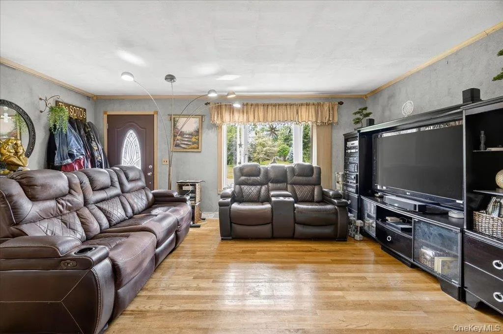 Living room featuring light wood finished floors and crown molding Living room featuring light wood finished floors and crown molding