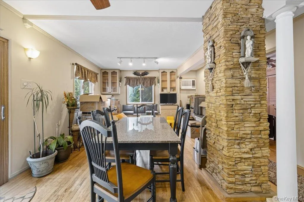 Dining space with light wood finished floors, crown molding, an AC wall unit, and decorative columns Dining space with light wood finished floors, crown molding, an AC wall unit, and decorative columns