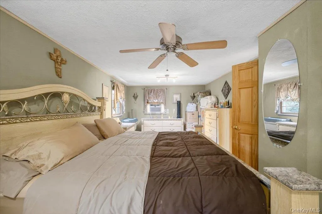 Bedroom featuring a textured ceiling, a ceiling fan, multiple windows, and crown molding Bedroom featuring a textured ceiling, a ceiling fan, multiple windows, and crown molding