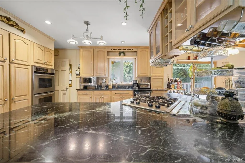 Kitchen with decorative light fixtures, glass insert cabinets, appliances with stainless steel finishes, dark stone counters, and recessed lighting Kitchen with decorative light fixtures, glass insert cabinets, appliances with stainless steel finishes, dark stone counters, and recessed lighting