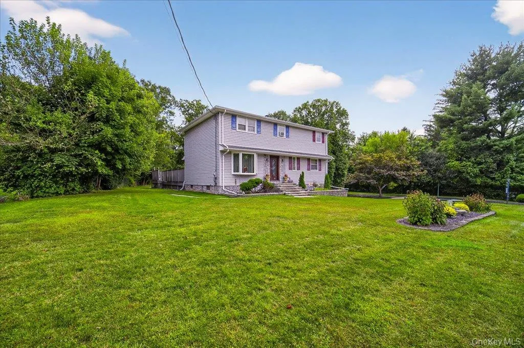 Back of house featuring a yard, view of wooded area, and crawl space Back of house featuring a yard, view of wooded area, and crawl space
