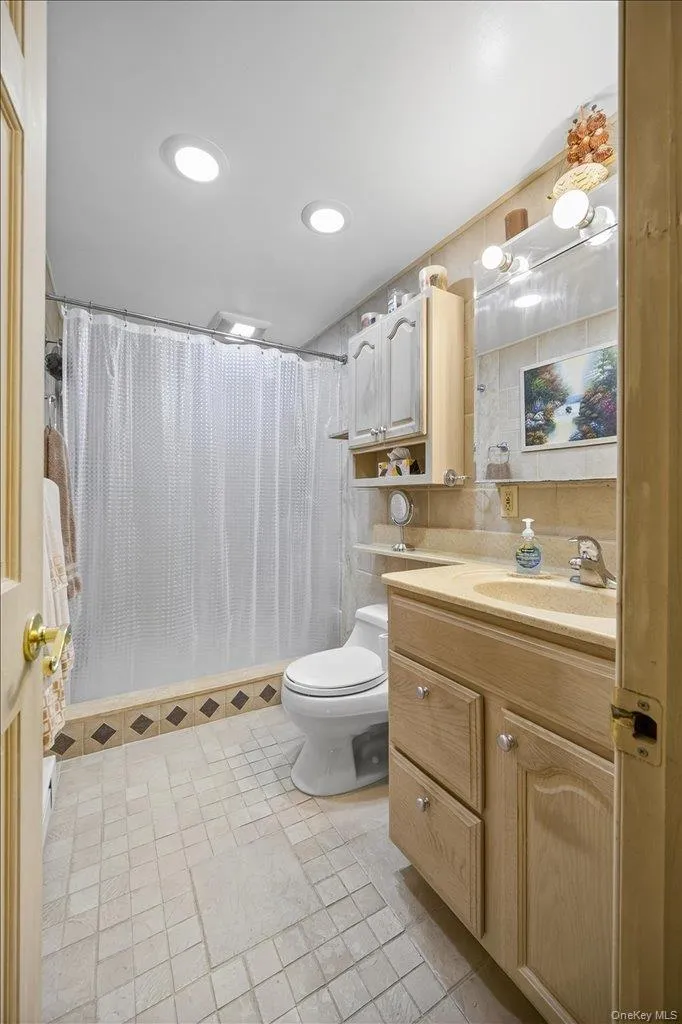 Full bathroom featuring vanity, a shower stall, light tile patterned flooring, recessed lighting, and tile walls Full bathroom featuring vanity, a shower stall, light tile patterned flooring, recessed lighting, and tile walls