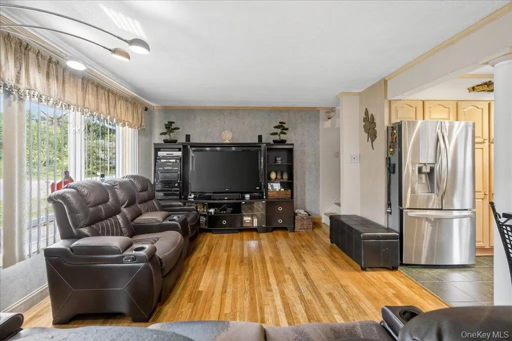 Living area featuring light wood finished floors and ornamental molding Living area featuring light wood finished floors and ornamental molding