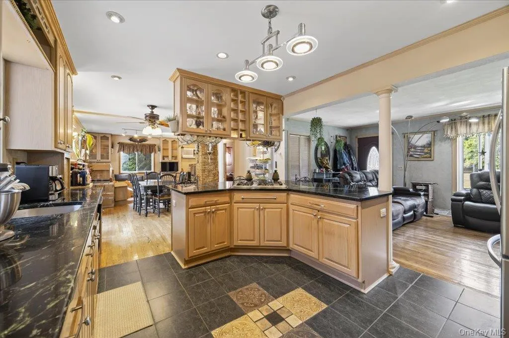 Kitchen with open floor plan, dark tile patterned floors, dark stone countertops, pendant lighting, and recessed lighting Kitchen with open floor plan, dark tile patterned floors, dark stone countertops, pendant lighting, and recessed lighting