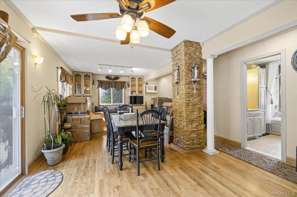 Dining area featuring decorative columns, crown molding, light wood-style flooring, and a ceiling fan Dining area featuring decorative columns, crown molding, light wood-style flooring, and a ceiling fan