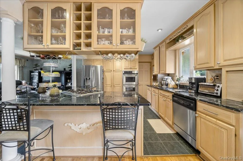 Kitchen with a kitchen breakfast bar, glass insert cabinets, tasteful backsplash, appliances with stainless steel finishes, and recessed lighting Kitchen with a kitchen breakfast bar, glass insert cabinets, tasteful backsplash, appliances with stainless steel finishes, and recessed lighting