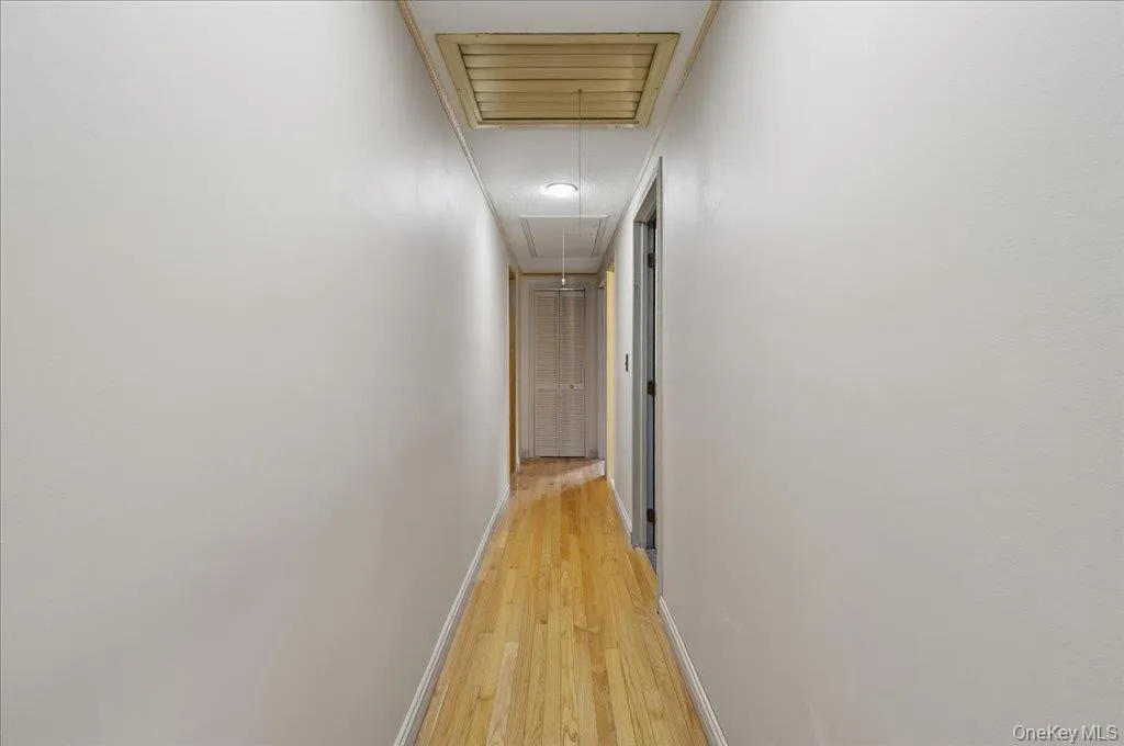 Hallway with attic access and light wood-type flooring Hallway with attic access and light wood-type flooring