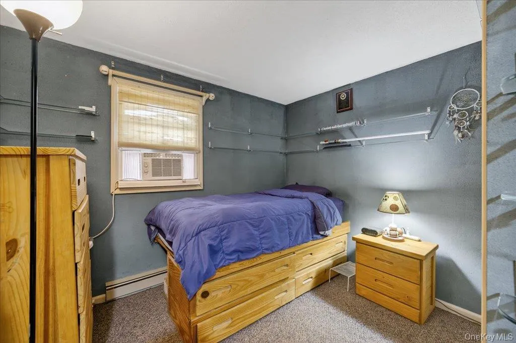 Carpeted bedroom with cooling unit and baseboard heating Carpeted bedroom with cooling unit and baseboard heating