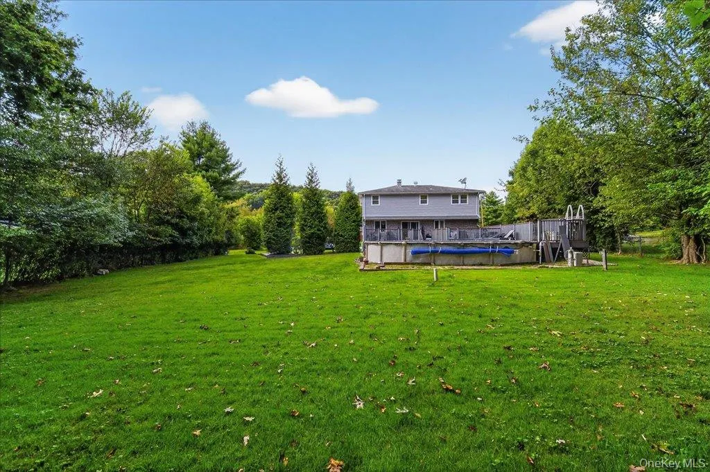 View of green lawn with a wooden deck and view of scattered trees View of green lawn with a wooden deck and view of scattered trees