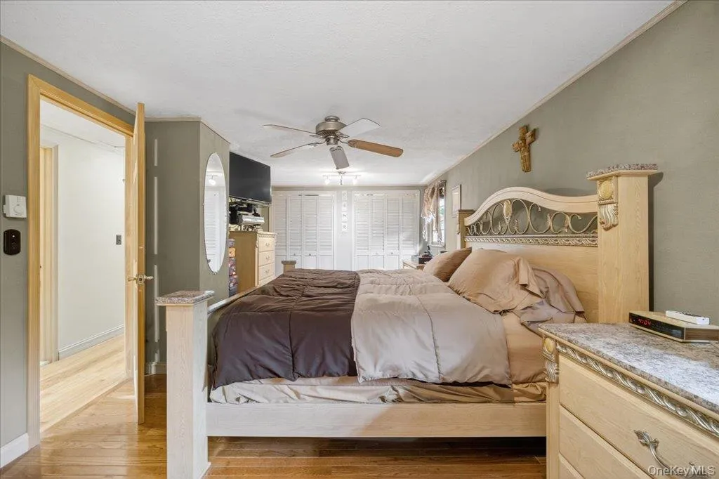 Bedroom featuring wood finished floors, two closets, and a ceiling fan Bedroom featuring wood finished floors, two closets, and a ceiling fan