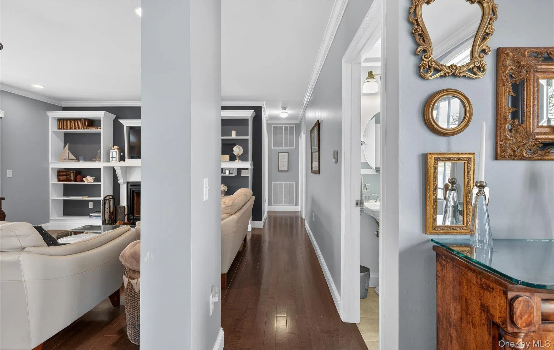 Hallway featuring dark wood finished floors, crown molding, and built in features Hallway featuring dark wood finished floors, crown molding, and built in features