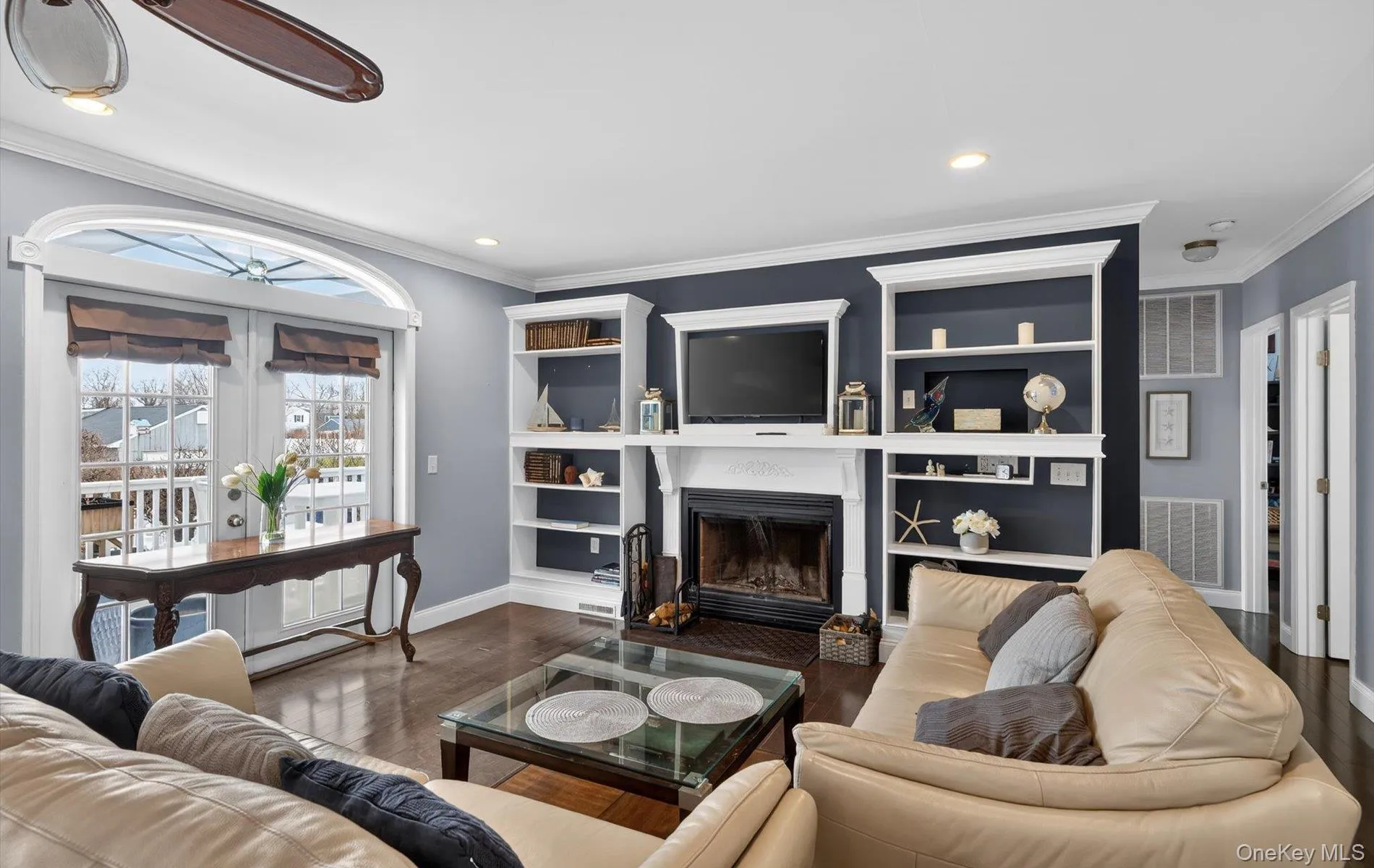 Living room with crown molding, a fireplace with flush hearth, wood finished floors, and recessed lighting Living room with crown molding, a fireplace with flush hearth, wood finished floors, and recessed lighting