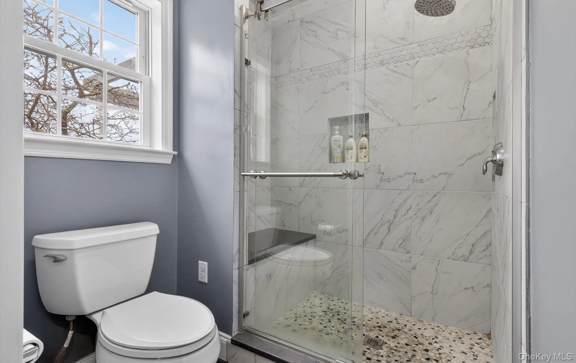 Bathroom featuring toilet and a marble finish shower Bathroom featuring toilet and a marble finish shower