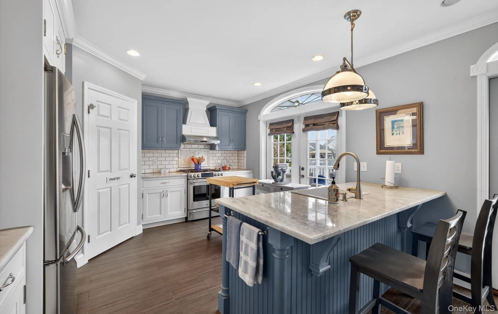 Dual tone kitchen with a breakfast bar area, a peninsula, light stone counters, stainless steel appliances, and decorative light fixtures Dual tone kitchen with a breakfast bar area, a peninsula, light stone counters, stainless steel appliances, and decorative light fixtures
