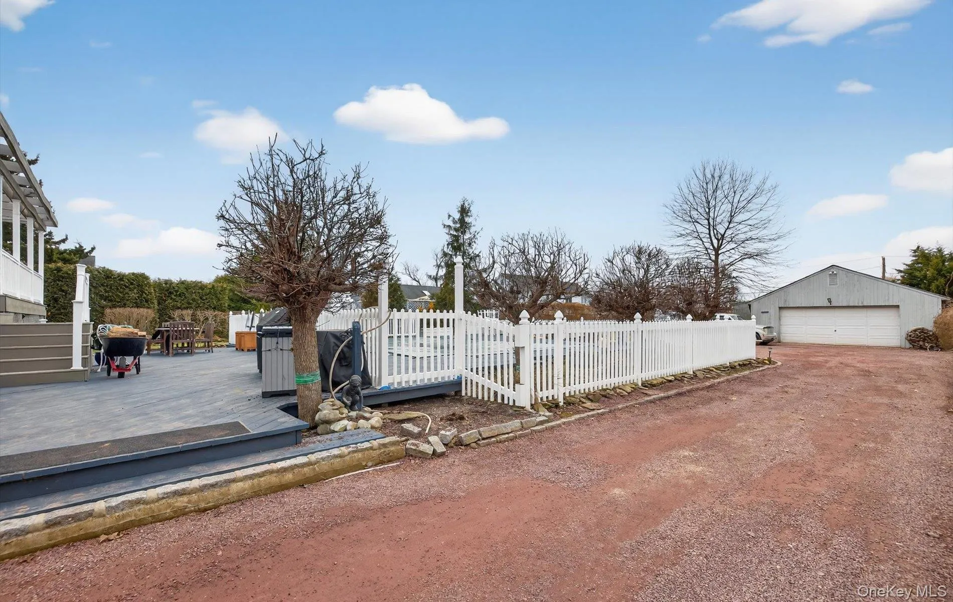 Fenced front yard with a deck, a garage, and an outbuilding Fenced front yard with a deck, a garage, and an outbuilding