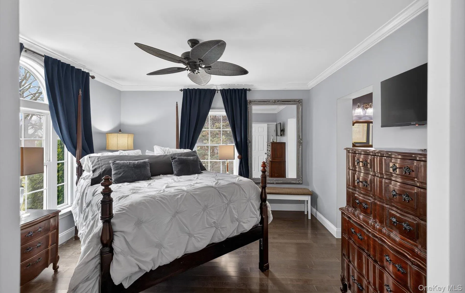 Bedroom featuring crown molding, dark wood-type flooring, and a ceiling fan Bedroom featuring crown molding, dark wood-type flooring, and a ceiling fan