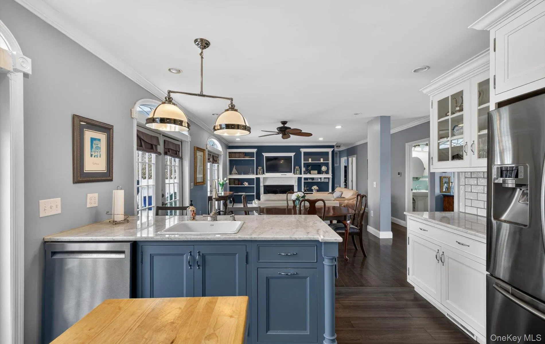 Dual tone kitchen featuring a peninsula, stainless steel appliances, open floor plan, ornamental molding, and light stone countertops Dual tone kitchen featuring a peninsula, stainless steel appliances, open floor plan, ornamental molding, and light stone countertops