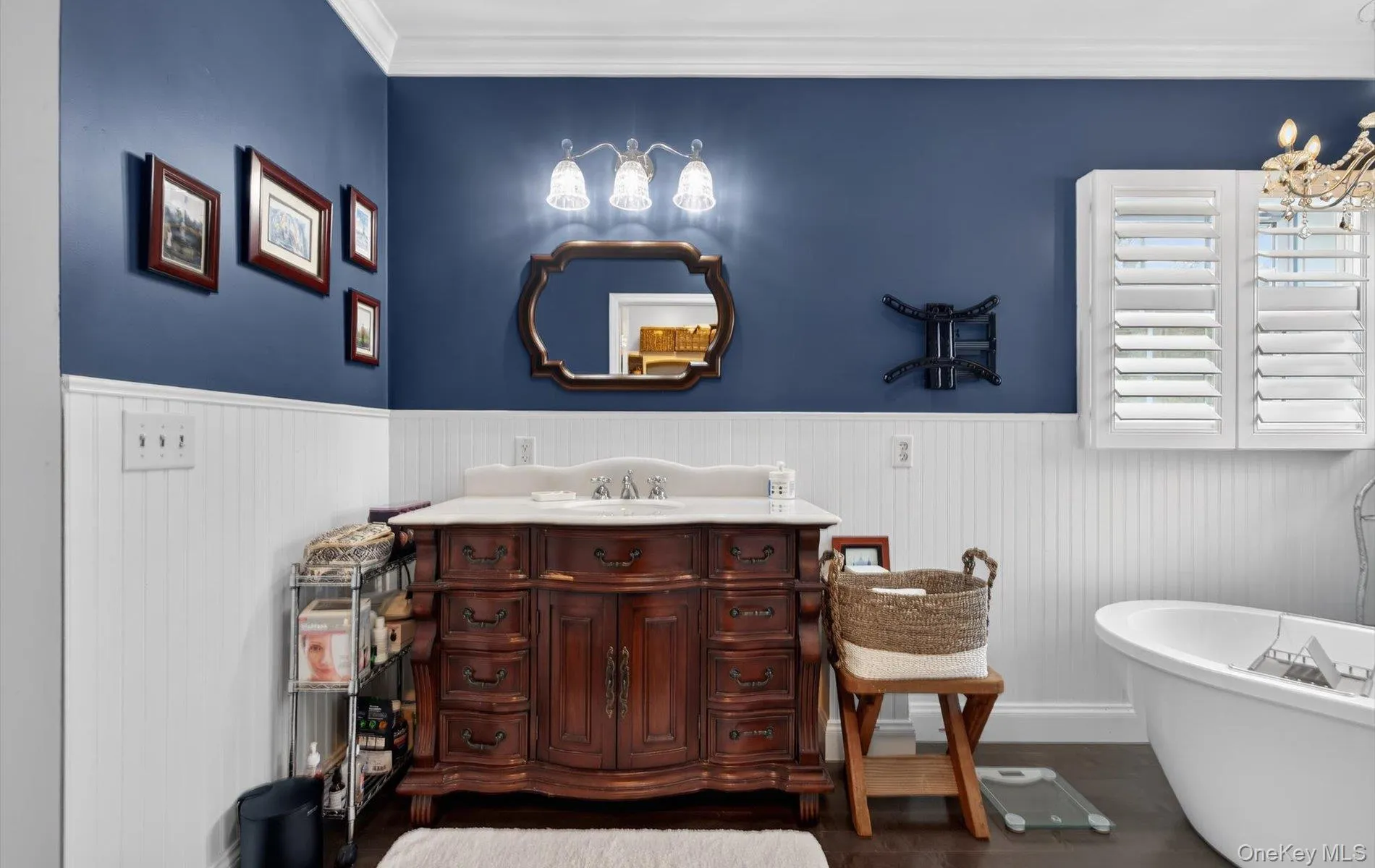 Full bathroom with vanity, a soaking tub, crown molding, dark wood-type flooring, and a wainscoted wall Full bathroom with vanity, a soaking tub, crown molding, dark wood-type flooring, and a wainscoted wall