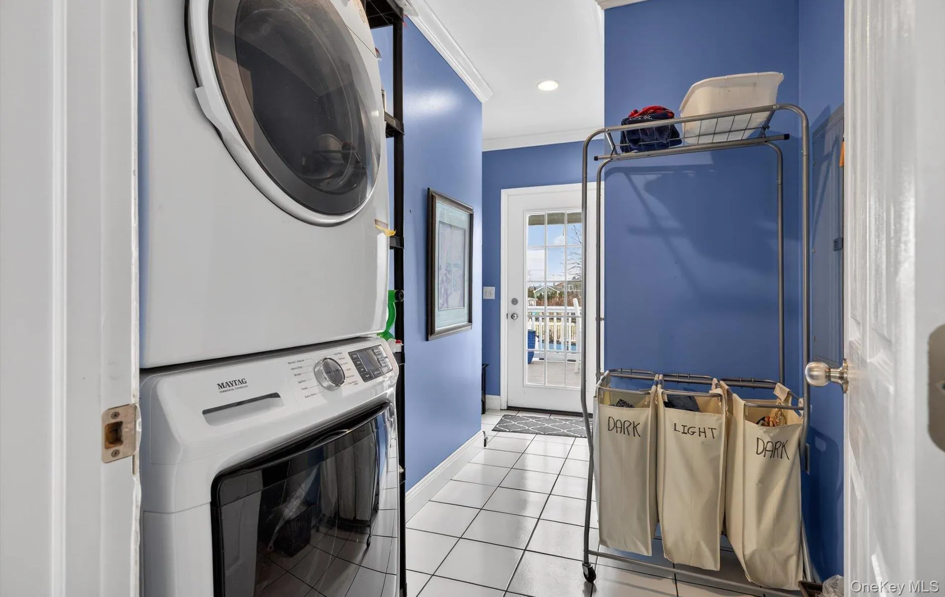 Laundry area with light tile patterned floors, stacked washer and dryer, crown molding, and recessed lighting Laundry area with light tile patterned floors, stacked washer and dryer, crown molding, and recessed lighting